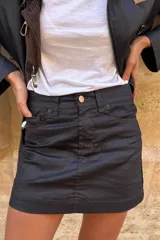 Minifalda negra de cuero sintético con costuras marrones.