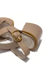 Sandalia de cuero color visón, con ajuste de hebilla dorada lateral y tacón de 8 cm.