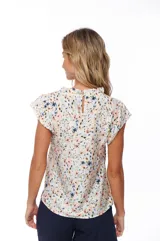Blusa estampada con flores en tonos rosa, azul y verde sobre fondo blanco. Tiene cuello redondo y mangas cortas con volados.