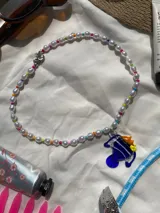 Collar corto de perlas blancas con mostacillas de colores y dije de vidrio con forma de pez azul, amarillo y naranja.