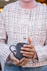 Chaqueta corta tipo Chanel de tweed color rosa, con botones fantasía y cuello redondo.