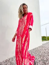 Vestido camisero largo con estampado batik en tonos rojo y beige, con cuello camisero y mangas largas con puños.