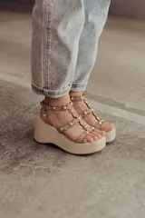 Sandalias negras de plataforma con tiras de gamuza y esferas doradas decorativas.