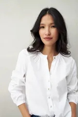 Camisa blanca de algodón con cuello mao con leve frunce, abotonadura frontal con botones de nácar y mangas amplias con puños fruncidos.