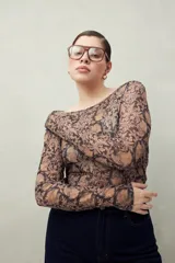 Top de manga larga en tejido translúcido con estampado animal print en tonos marrones y negros. Diseño ajustado con transparencia.