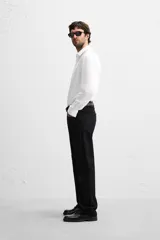 Camisa blanca de corte slim fit, confeccionada en algodón, con cuello italiano, mangas largas con puños abotonados y cierre frontal con botones.