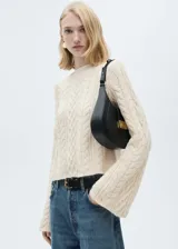 Sweater color crema de tejido de punto trenzado, con cuello redondo y mangas acampanadas.