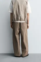 Pantalón cargo de algodón color marrón con efecto lavado, corte relajado y tiro medio. Presenta cintura elástica con botón y cierre de cremallera, bolsillos delanteros, bolsillos plastrón en la espalda y grandes bolsillos cargo en las perneras.