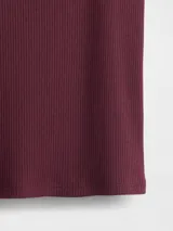 Remera de manga corta ajustada al cuerpo, color gris claro, con tejido acanalado (rib). Presenta un escote redondo amplio.