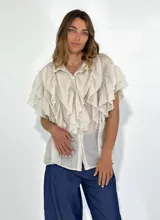 Camisa color crudo con cuello clásico, cierre frontal con botones y mangas cortas con volados.