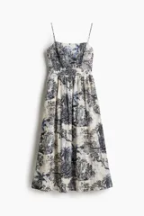 Vestido midi con breteles finos, escote cuadrado y espalda fruncida. Presenta un estampado de tigres, elefantes y vegetación en tonos azules sobre fondo blanco.