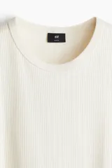 Musculosa blanca de punto acanalado, con cuello redondo y corte ajustado.