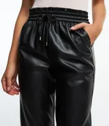 Pantalón zanahoria color marrón claro confeccionado en material sintético con cintura elástica, cordón ajustable con punteras metalizadas, bolsillos laterales y traseros.