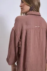 Camisa de lino color terracota, con cuello camisero, botones frontales y mangas amplias de tres cuartos.