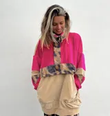 Buzo de corte amplio con cuello alto con cierre parcial de botones, mangas largas con puños elásticos, parte superior fucsia, parte inferior beige y detalles con estampado animal print.