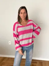 Sweater tejido a rayas fucsia y gris, con calce relajado, mangas amplias y cuello en V.