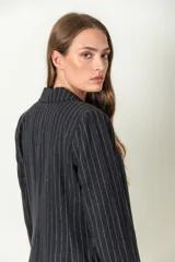 Blazer negro con finas rayas verticales blancas, solapas clásicas y cierre con dos botones.