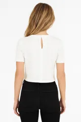 Remera color crema de algodón con bordados en el pecho y nudo en la cintura.