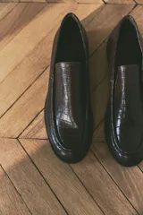 Mocasines marrones con textura de piel de cocodrilo, costura tradicional en la parte delantera, forro de lona de algodón y suela de goma. Tacón de 1 cm.