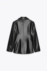 Blazer entallada negra de efecto piel, con cuello solapa y manga larga. Tiene bolsillos de plastrón en el delantero, costuras marcadas y forro interior combinado a tono. El cierre es frontal con botón interior y exterior.