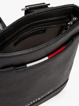 Bandolera negra de Tommy Hilfiger con acabado granulado, correa ajustable de tejido trenzado, bolsillo exterior abierto, cinta distintiva y logo metálico.