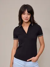 Remera polo negra de manga corta con cuello sin botones y detalles de doble línea blanca en cuello y mangas.