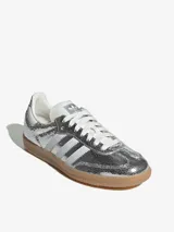 Zapatillas Adidas Samba OG W plateadas metalizadas con efecto craquelado, las tres tiras laterales blancas y suela de goma color caramelo.