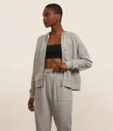 Campera deportiva gris de modal, con capucha ajustable con cordón, cierre frontal con cremallera y bolsillos laterales.
