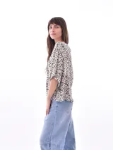 Blusa negra con cuello redondo y abotonadura frontal parcial. Tiene mangas cortas amplias y corte holgado.