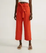 Pantalón clochard color naranja, con cintura elástica, cinturón para atar, cierre por cremallera, pliegues delanteros y barra doblada.