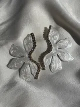 Aros colgantes con forma de flor blanca y detalle de strass con cierre a presión de acero inoxidable.