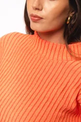 Buzo de punto color coral, con cuello alto y diseño relajado, presentado en un tejido suave y abrigado.