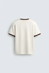 Camiseta color crudo de corte relaxed fit, con cuello redondo y mangas cortas con ribete marrón. Estampado frontal con la frase "Golden Hour" en color marrón.