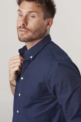 Camisa de hombre color crema, de corte clásico, con cuello abotonado y mangas largas.