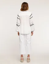 Blusa blanca de manga larga con bordados negros en cuello, mangas y frente.