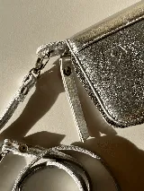 Billetera grande de cuero color verde oliva con correa de hombro desmontable. Tiene espacio para tarjetas, billetes, documentos y un bolsillo con cierre.