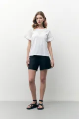 Remera blanca con detalles de broderie y manga corta, de corte suelto y diseño fresco.