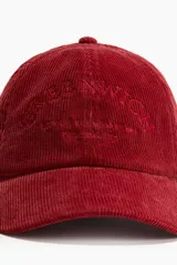 Gorra de béisbol color borgoña de pana con bordado frontal y correa trasera ajustable.