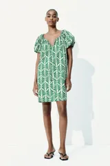 Vestido corto evasé de algodón con estampado de hojas verdes. Tiene mangas globo cortas de diseño raglán, escote redondo con cordón para ajustar y corte holgado.