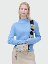 Bandolera Marc Jacobs modelo The Wild Daisy Snapshot, color crema con estampado de flores de colores, logo plateado en el frente y correa ancha ajustable con monedero extraíble.