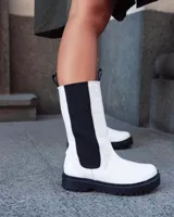 Botas blancas de caña alta con elástico lateral marrón y suela track negra.