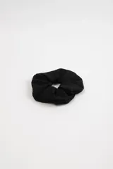 Scrunchie negro de tela con textura pointelle.
