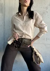 Camisa beige de manga larga con bordado floral, cuello clásico y cierre frontal con botones. Corte recto y holgado.