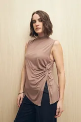 Musculosa color marrón topo de cuello alto, sin mangas, con terminación en pico y abertura lateral con detalle de nudo.