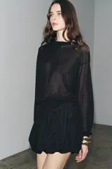 Falda pantalón corta negra de tiro medio, con cintura elastizada y detalle de tejido con volumen y pliegues. Cierre lateral con cremallera oculta.