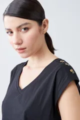 Remera verde pistacho de corte recto, con cuello en V y botones decorativos en los hombros.