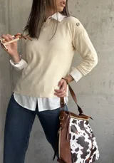 Sweater beige de hilo con cuello camisero blanco y botones decorativos en los hombros.