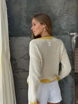 Sweater tejido a mano en Uruguay, 100% lana merino color crudo, con cuello, puños y ruedo en amarillo. Presenta un corazón amarillo en el frente.