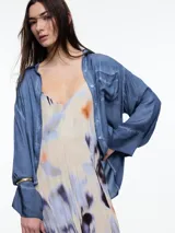 Camisa gris de manga larga confeccionada en viscosa teñida en frío, con efecto gastado. De corte relajado, con bolsillo delantero y puños amplios.