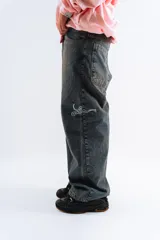 Pantalón de jean azul oscuro con efecto desgastado, corte mega baggy, bolsillos grandes y bordado lateral con el logo de la marca en color blanco.